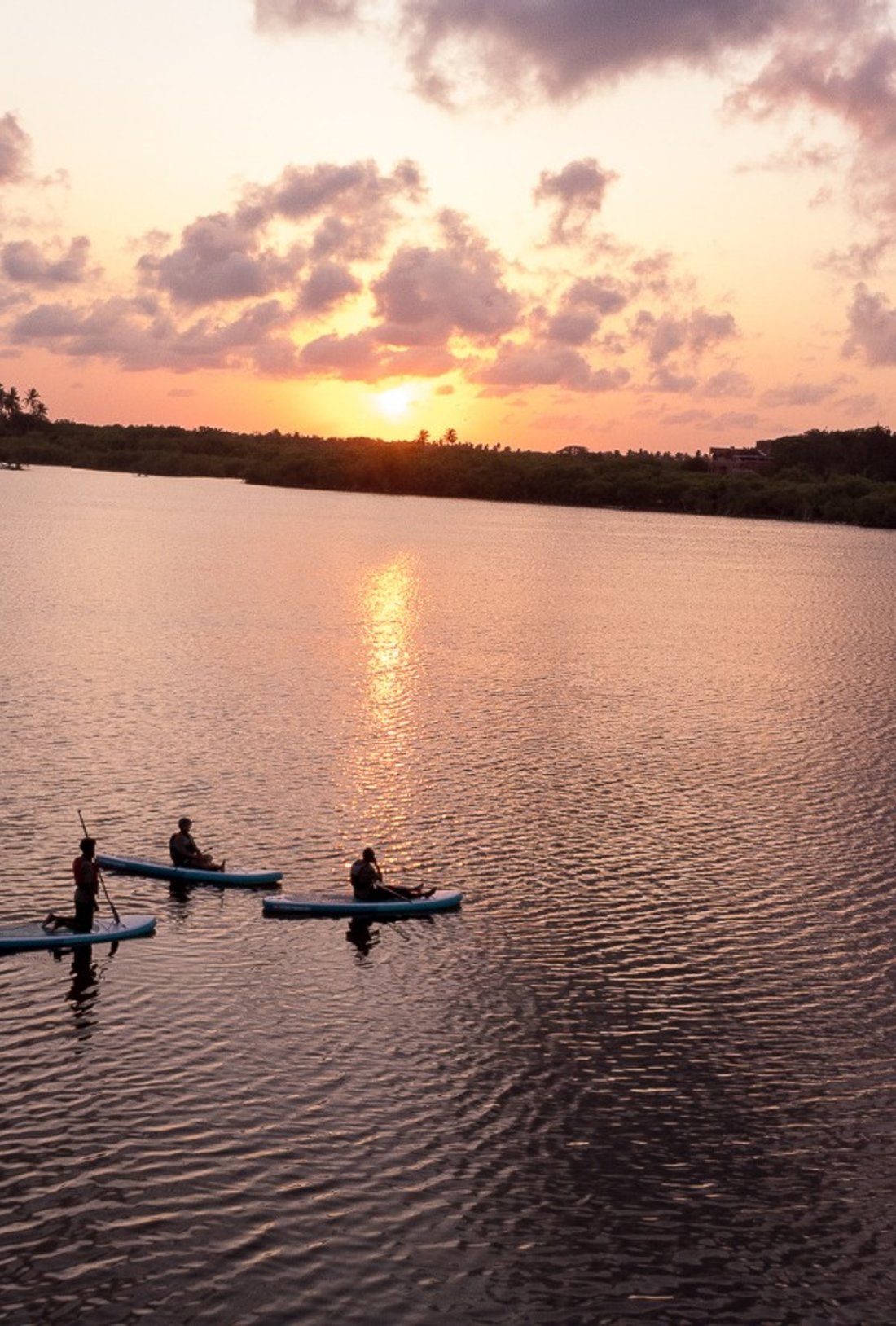 a paddler on the board with the sun setting in the background